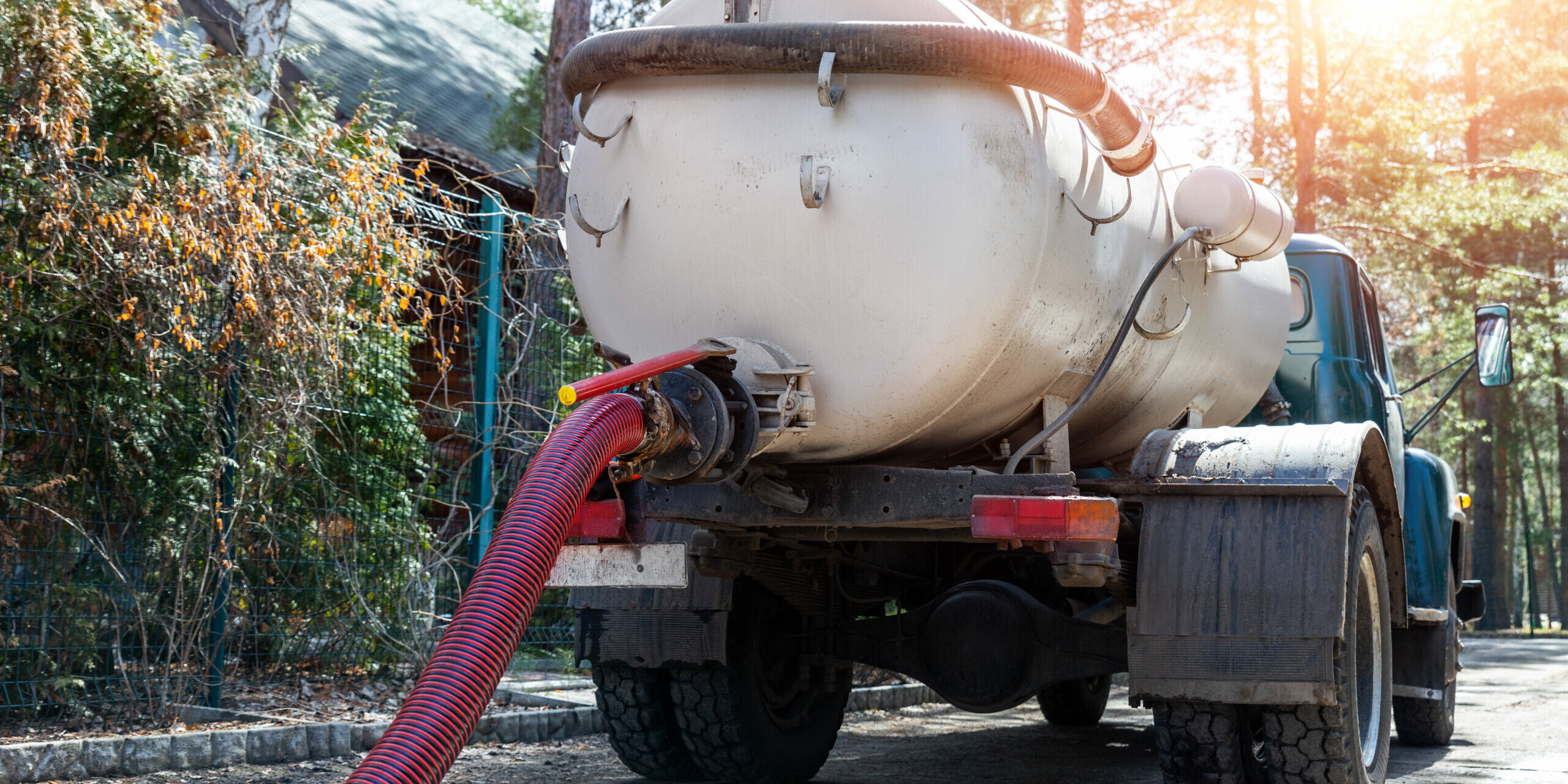 Close Up Pipe Hose Of Sewage Truck Car Engine Emptying Home Sewerage Tank. Septic Cleaning Vacuum Service And Maintenance Suburban Countryside Home. Suction Vehicle Cleaner Machine Pumping Drainage