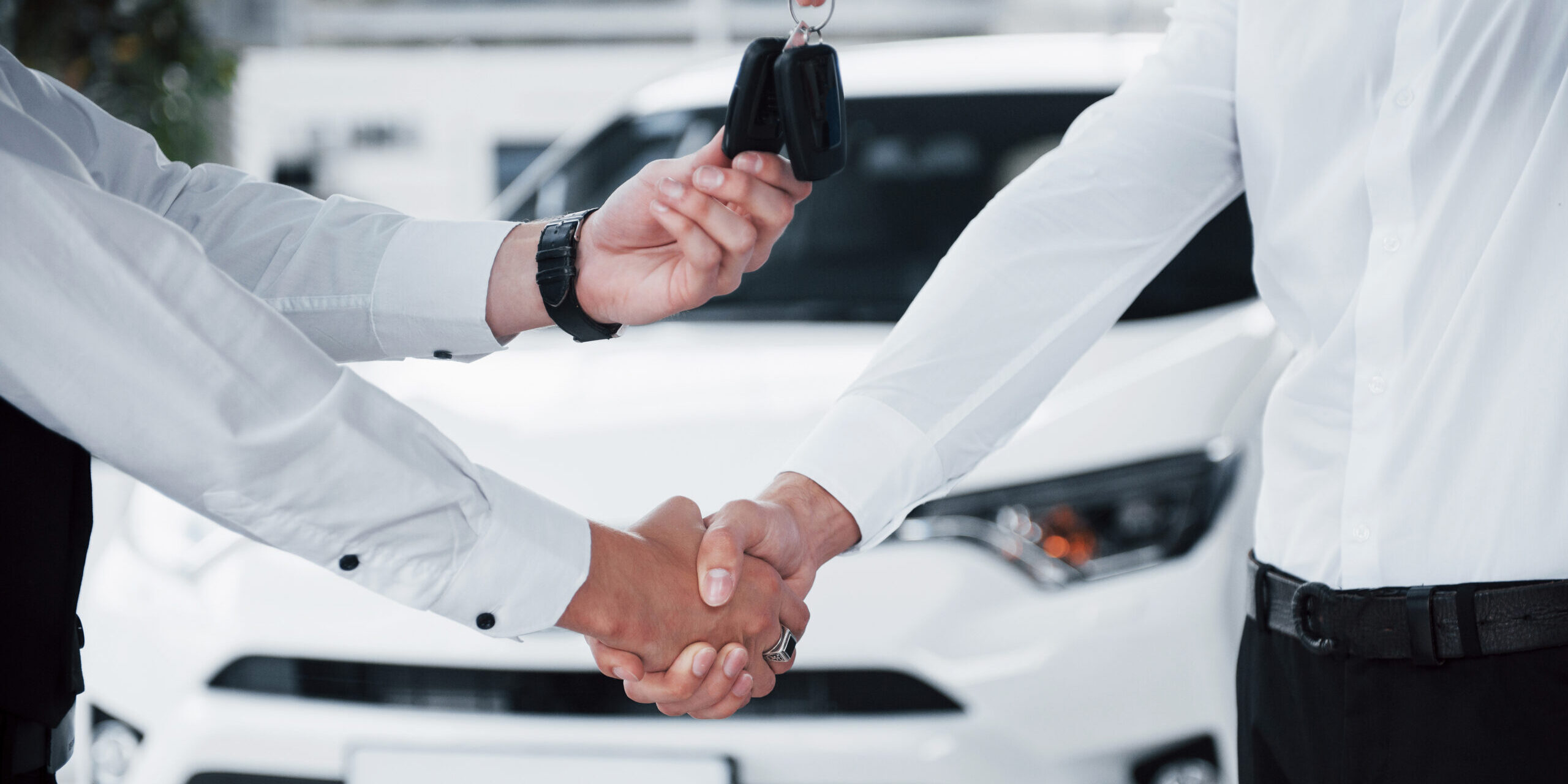 Close up of sales manager in black suit selling the car to the customer Close Up Of Sales Manager In Black Suit Selling The Car To The Customer