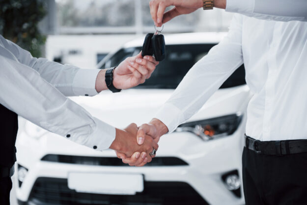 Close up of sales manager in black suit selling the car to the customer Close Up Of Sales Manager In Black Suit Selling The Car To The Customer