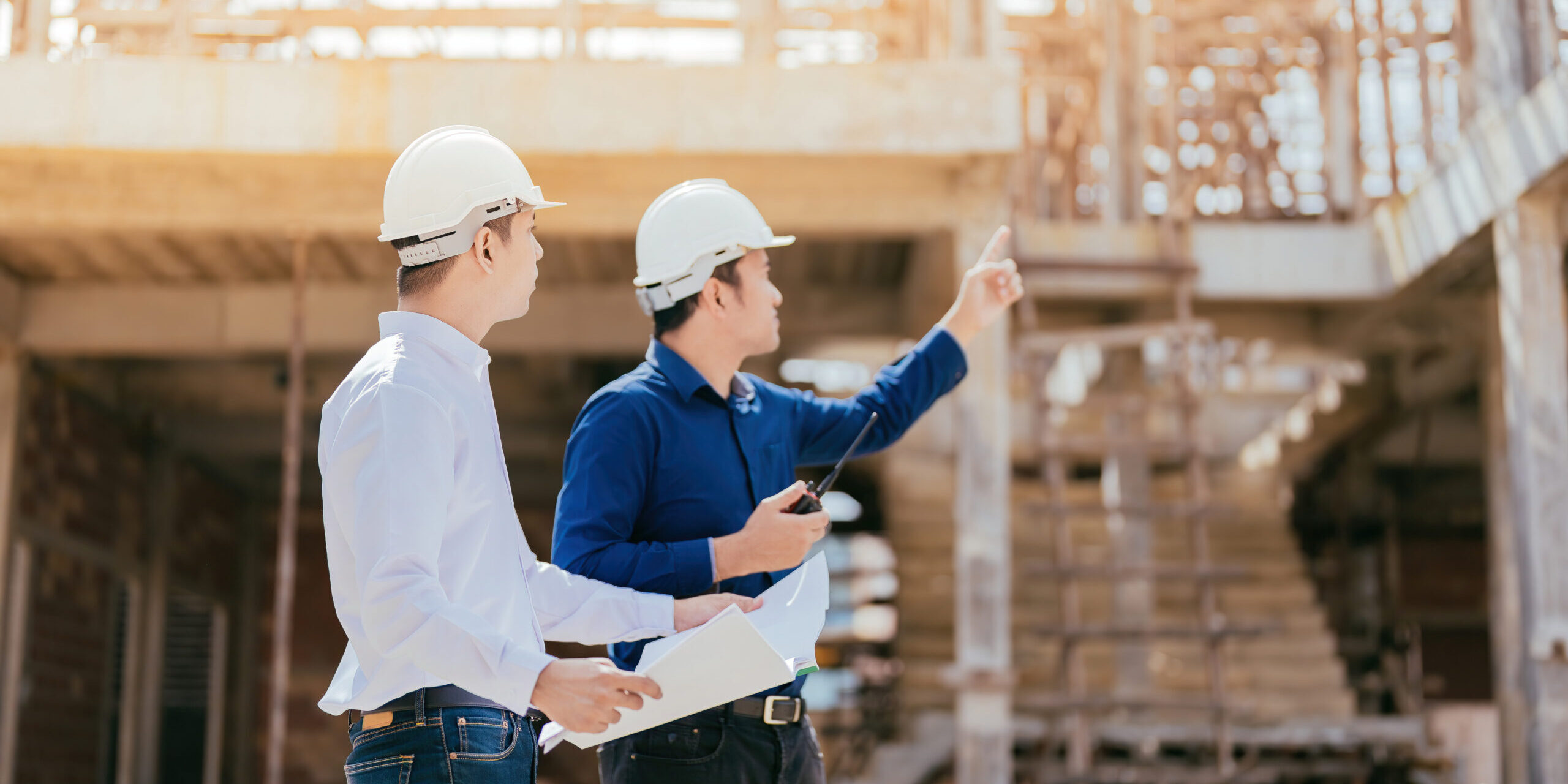 Half Body Photo Of A Team Of Asian Engineers, 2 Males As A Manager Look And Point To The Destination Use Blueprint In Design, Construction, Architecture Industry Use Radio Communication Wear A Helmet