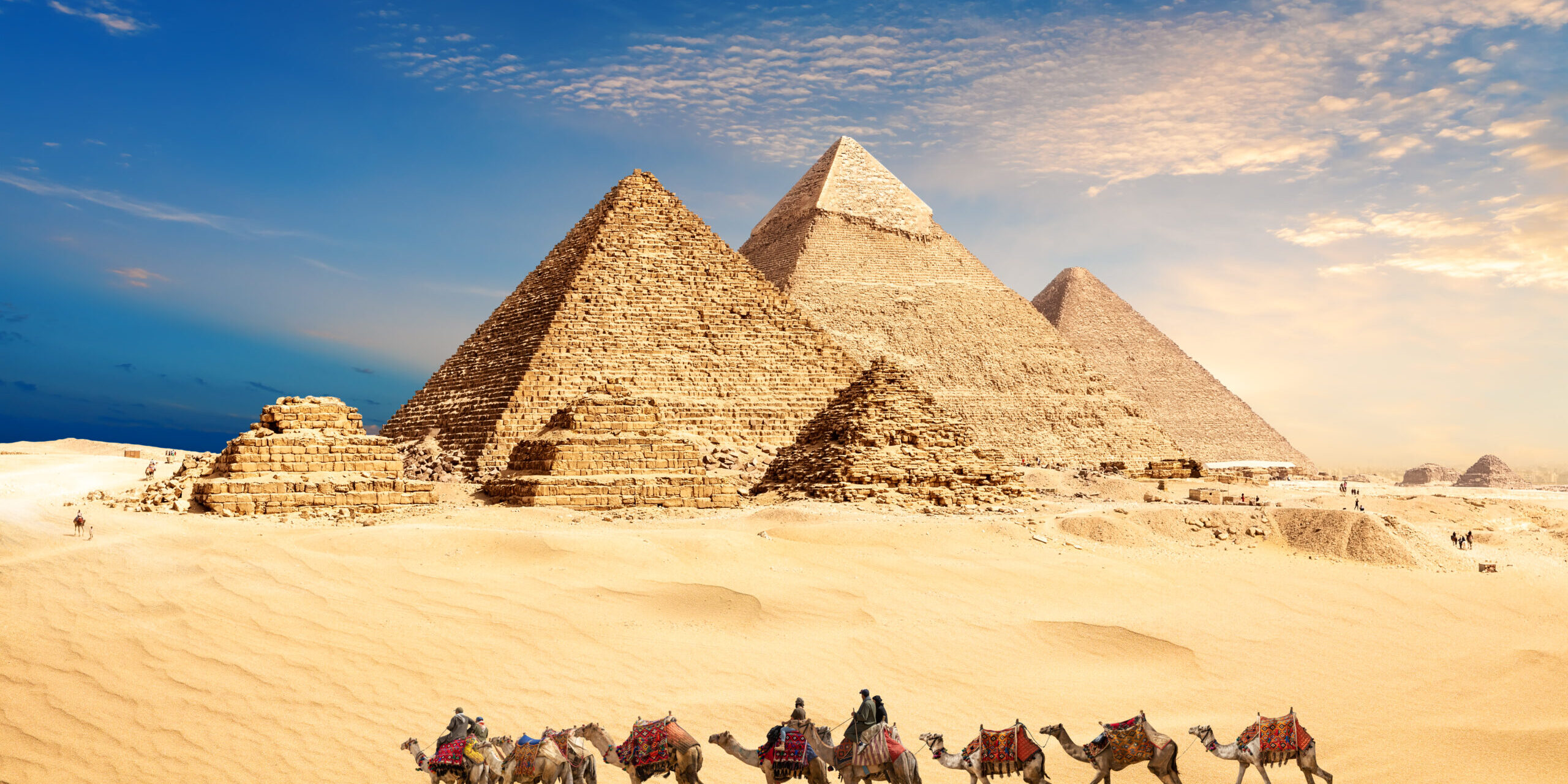 A camel caravan with bedouins by the Pyramids of Egypt in the desert of Giza A Camel Caravan With Bedouins By The Pyramids Of Egypt In The Desert Of Giza
