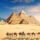 A Camel Caravan With Bedouins By The Pyramids Of Egypt In The Desert Of Giza